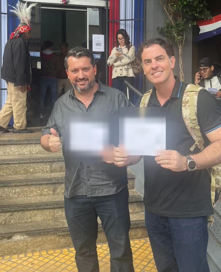 André e Felipe com o comprovante do processo, em frente à Dirección Nacional de Migraciones, em Assunção