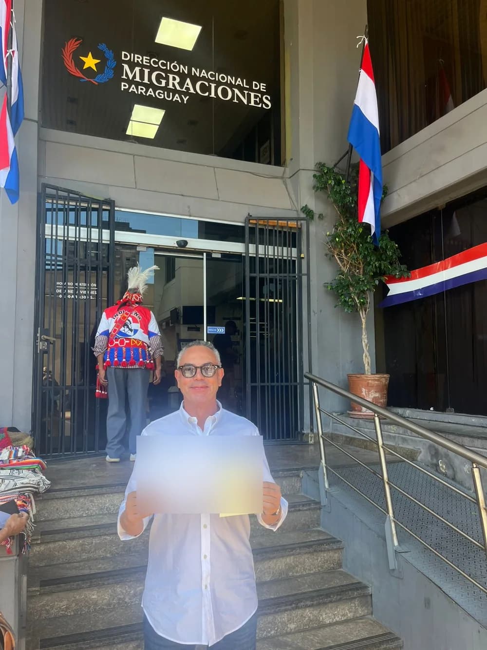 Décio com o comprovante e a cédula do processo, em frente à Dirección Nacional de Migraciones, em Assunção