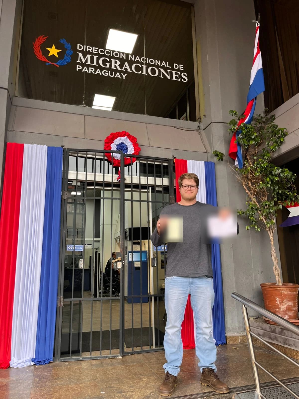 Matheus com os documentos da residência, em frente à Dirección Nacional de Migraciones, em Assunção