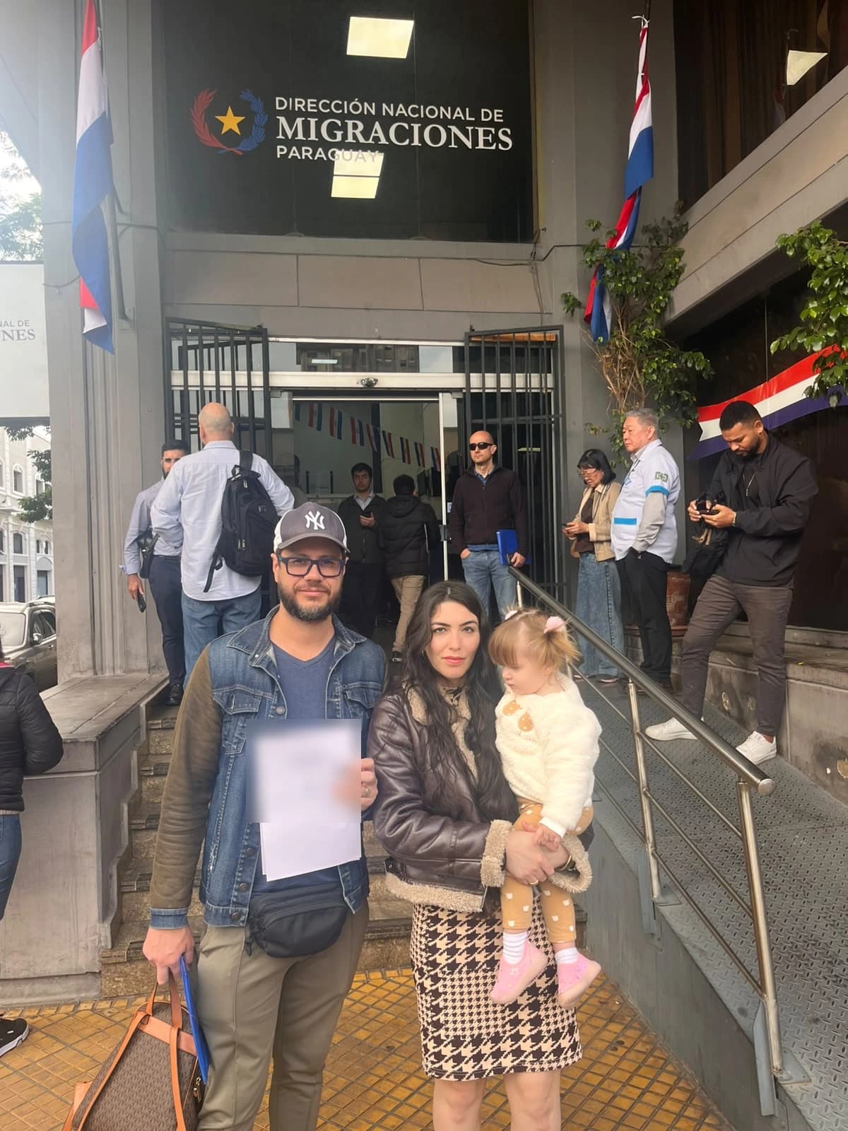 Peter e família com o comprovante do processo, em frente à Dirección Nacional de Migraciones, em Assunção