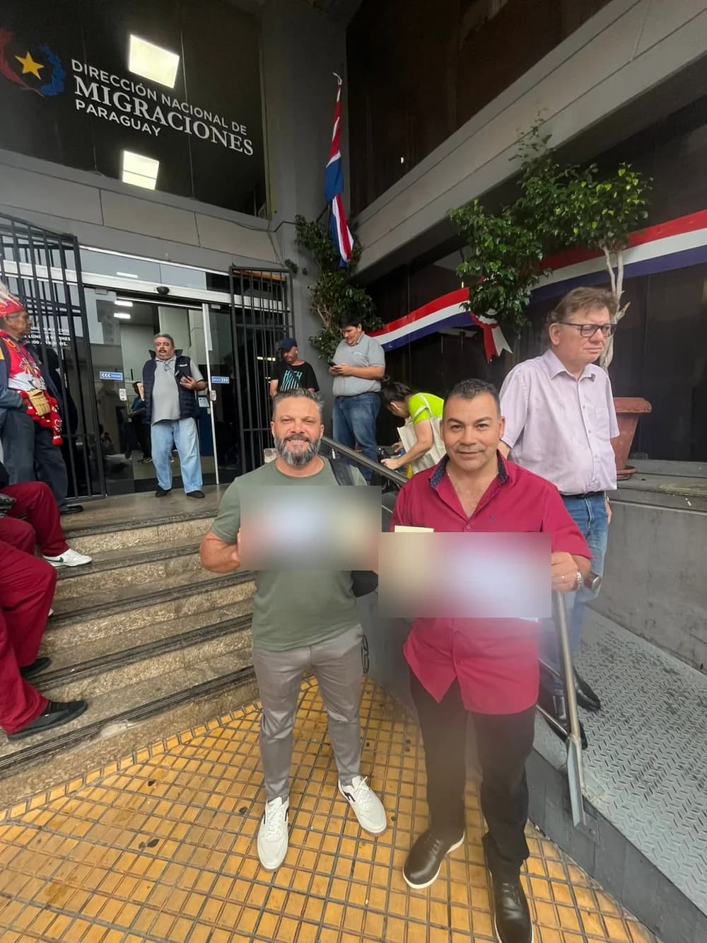 Roni e Carlos com os comprovantes do processo, em frente à Dirección Nacional de Migraciones, em Assunção
